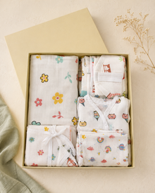 Maison Joey muslin baby gift box with assorted playful essentials on a warm ivory editorial background