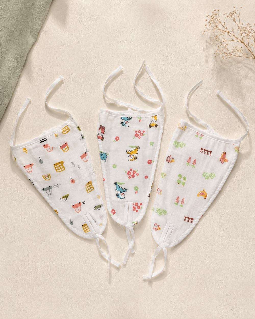 Maison Joey pack of three tie-on muslin nappies in assorted playful prints on a warm ivory editorial background