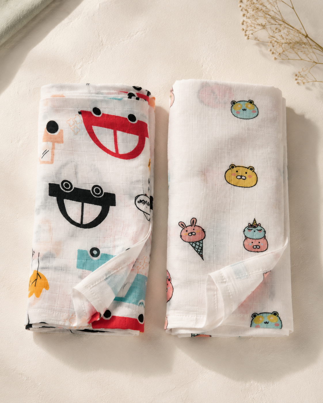 Maison Joey pack of two muslin swaddles in car and ice-cream prints on a warm ivory editorial background