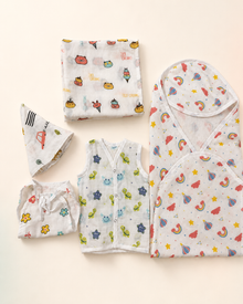 Maison Joey muslin baby gift set on a seamless warm ivory studio background